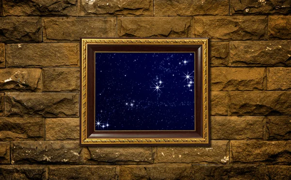 A photo of a wood frame on brick wall with the night sky setting inside — Stockfoto