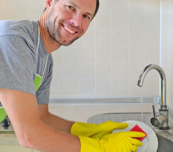 Smiling man washing dish in the kitchen — Stock Photo, Image