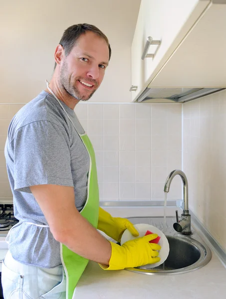 Sorrindo homem lavar prato na cozinha — Fotografia de Stock