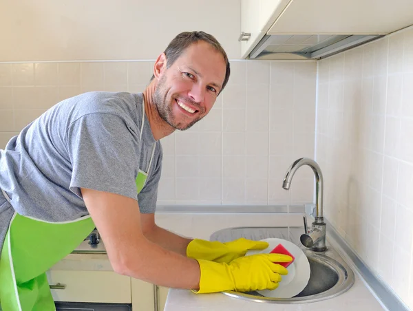 台所で皿を洗う男の笑顔 ストック画像