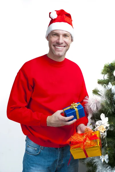 Sorrindo homem de Natal vestindo um chapéu de Papai Noel na árvore de Natal — Fotografia de Stock
