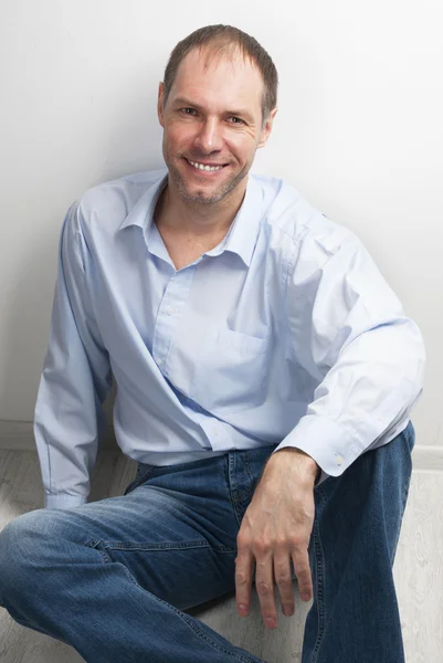 Portrait of smiling man sitting on the floor — Stock Photo, Image