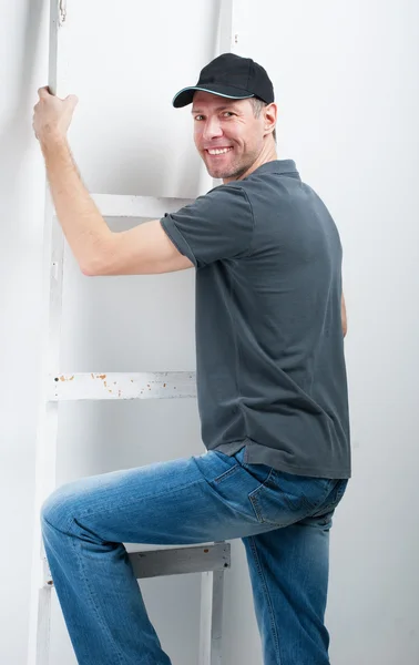 Χαμογελαστός άνθρωπος εργαζόμενος κρατήστε μια σκάλα σε λευκό φόντο — Φωτογραφία Αρχείου