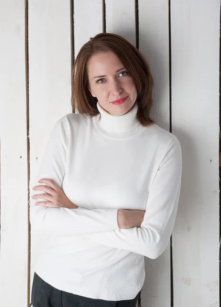 Femme souriante en col de poloneck blanc au mur de bordure — Photo