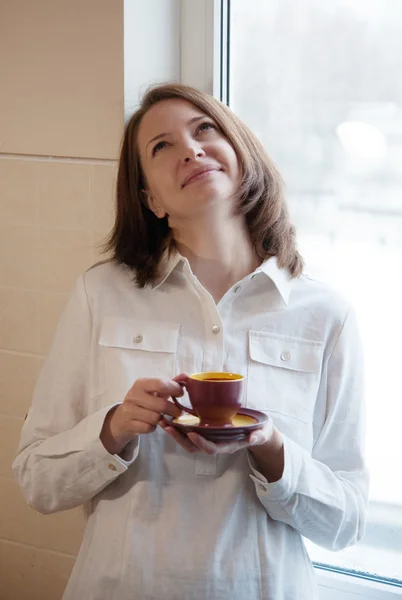 Beautiful woman at window with cup of coffee — Stock Photo, Image