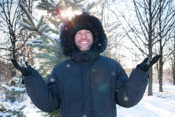 Smiling man wearing fur hooded parka coat in the winter park — Stock Photo, Image