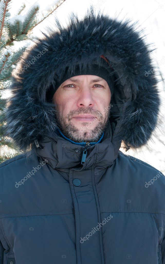 Portrait of confident man wearing fur hooded parka coat at the s