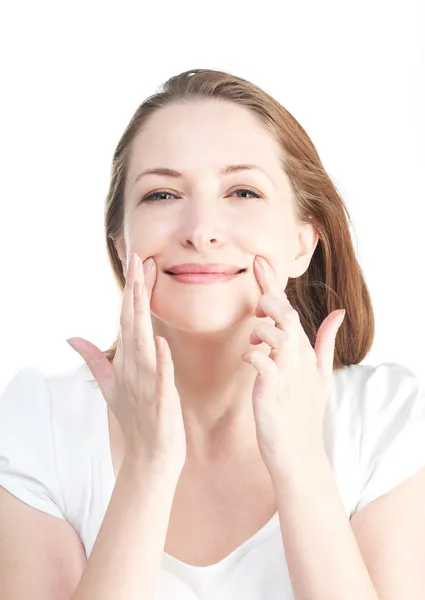 güzel bir kadın beyaz arkasında izole yüz egzersizleri yapar