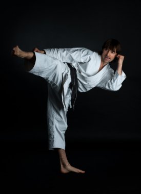 Ayağını siyah bir arka plan ile tekme karate yapan erkek