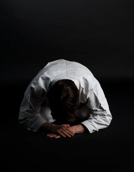 Karate uomo in kimono facendo fiocco tradizionale su un backgroun nero — Foto Stock