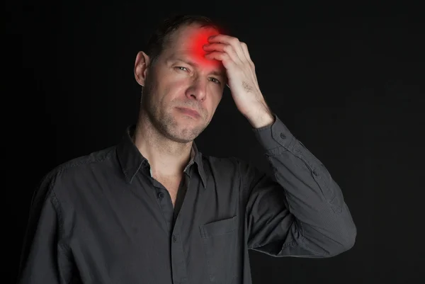 Un uomo con la testa dolorante che le tiene la mano. Sullo sfondo nero — Foto Stock