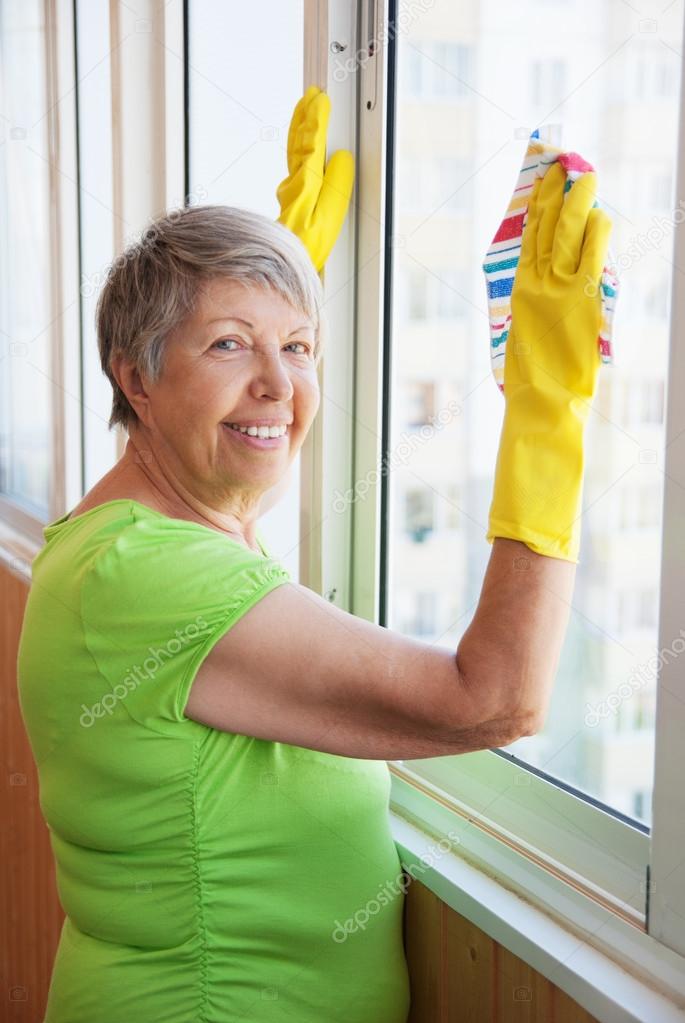 Smiling elderly woman cleaning a window