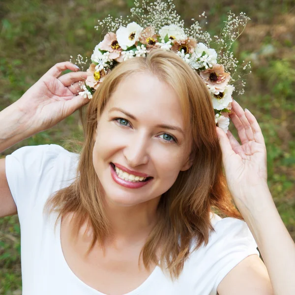 Girl in a wreath of flowers on a background of forest green — Stock Photo, Image