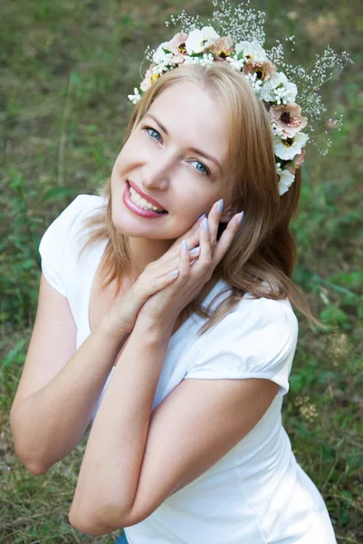 Girl in a wreath of flowers on a background of forest green — Stock Photo, Image