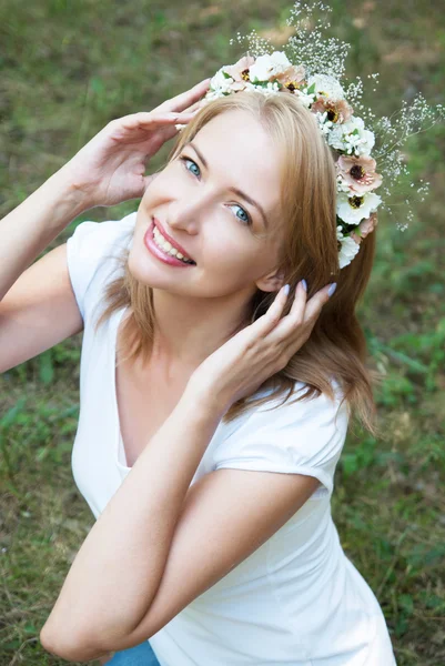 Girl in a wreath of flowers on a background of forest green — Stock Photo, Image