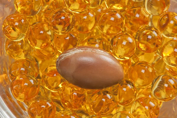 A seed of argan with yellow cosmetic pearl — Stock Photo, Image
