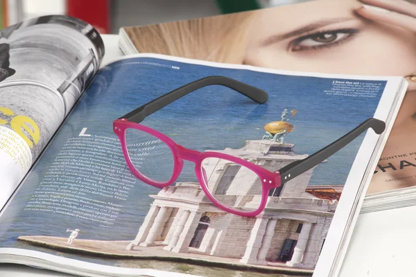 Óculos de leitura endossados em uma revista em casa — Fotografia de Stock