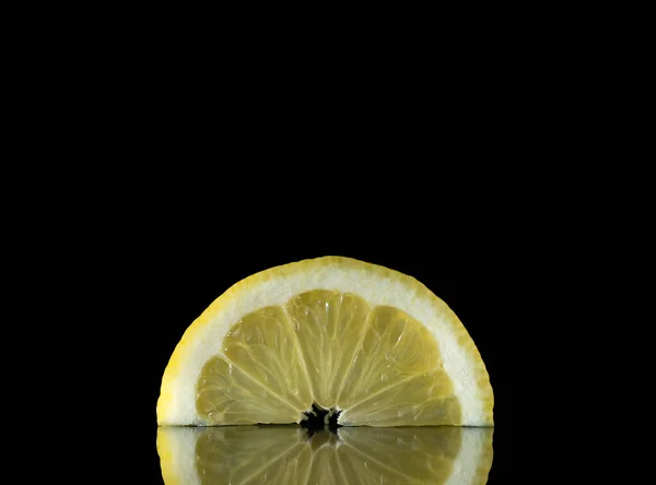 Лимонные ломтики на черном фоне, цитрусовые в отражении — стоковое фото