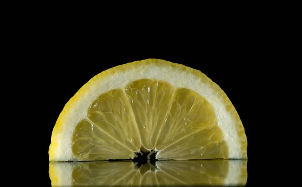 Лимонные ломтики на черном фоне, цитрусовые в отражении — стоковое фото
