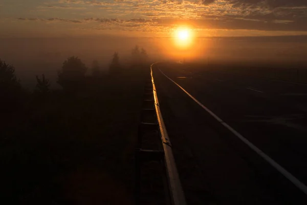 The road going into fog towards the rising sun — Stock Photo, Image