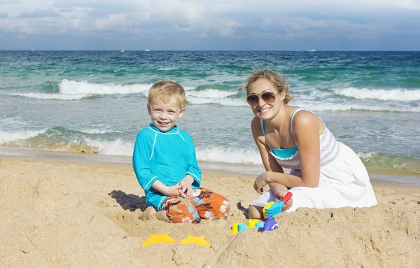 Familj spelar i sanden på stranden — Stockfoto