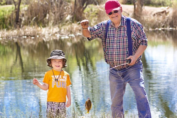 Küçük çocuk ve dedesi bir balık yakalamak — Stok fotoğraf