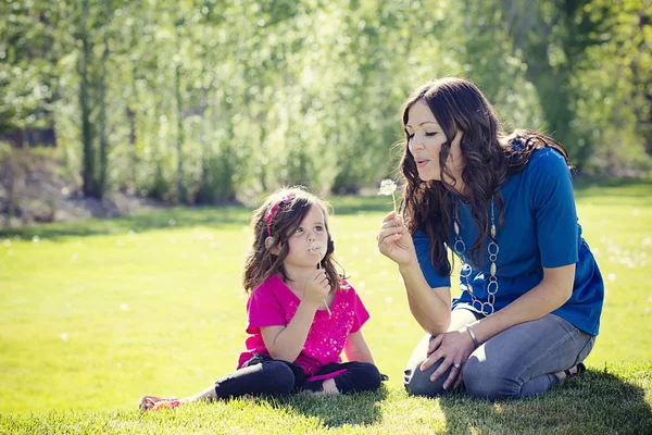 Mother Blowing Dandelions with daughter — Stock Photo, Image