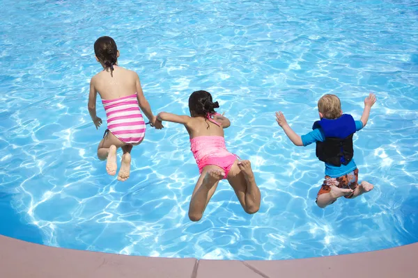 Troje dzieci, skoki do basenu — Zdjęcie stockowe