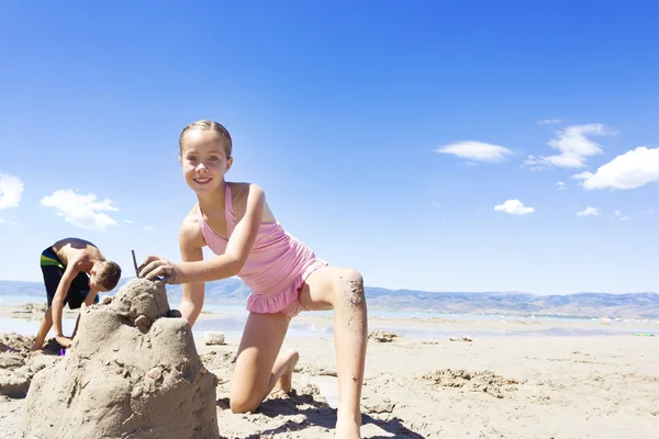 Menina construindo um castelo de areia na praia — Fotografia de Stock