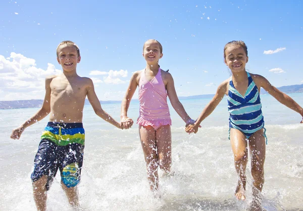 Niños salpicando y jugando en el océano — Foto de Stock