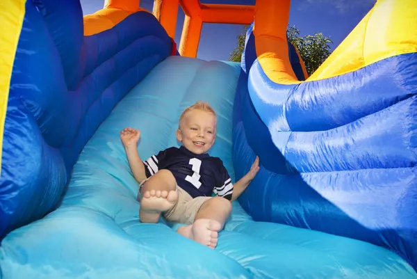 Niño deslizándose por un lado inflable —  Fotos de Stock