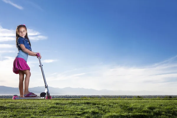 Menina bonito montando uma scooter ao ar livre — Fotografia de Stock