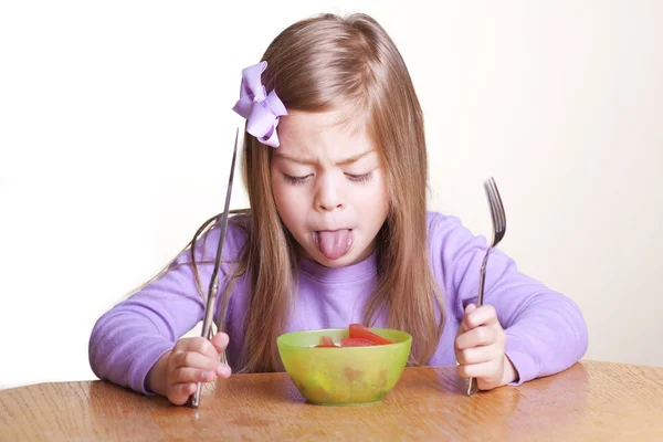 Seorang gadis kecil yang lucu terlihat jijik pada mangkuk sayurannya — Stok Foto