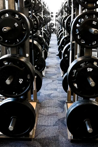 Fila larga de nuevo equipo de entrenamiento con pesas en un gimnasio — Foto de Stock