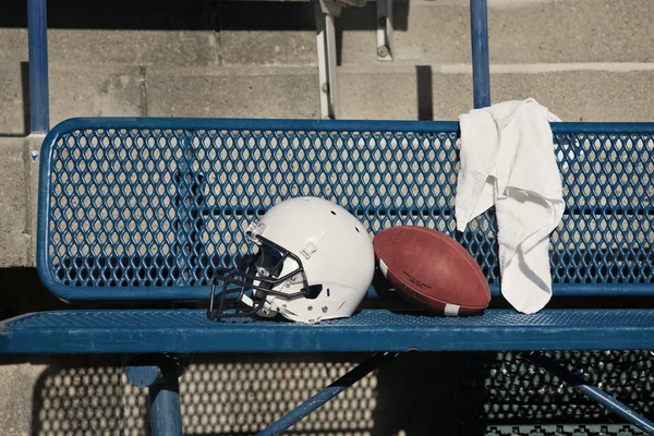 在一条长凳上的橄榄球头盔 — 图库照片