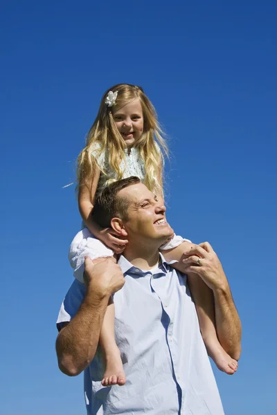 Jong meisje op de schouders van haar vaders — Stockfoto