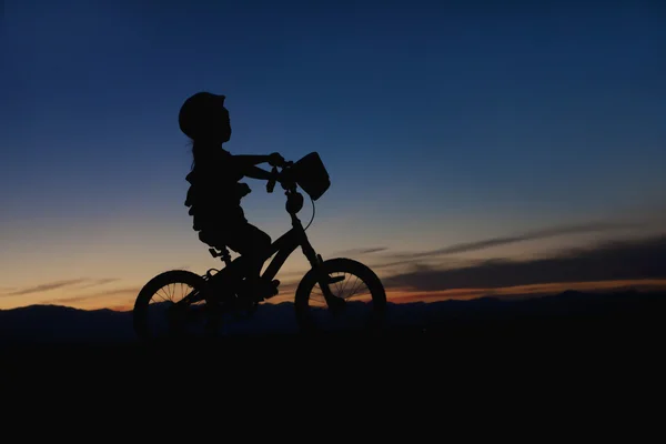 Flicka ridning cykel vid solnedgången — Stockfoto