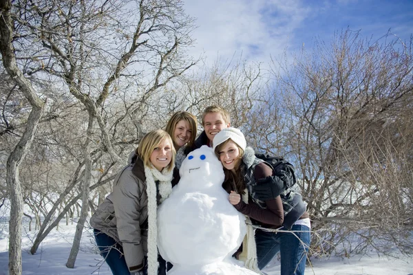 Молодые люди со снеговиком — стоковое фото