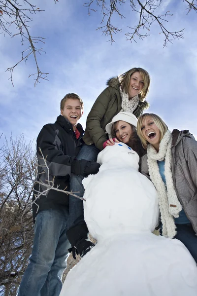Mladí lidé s sněhulák — Stock fotografie