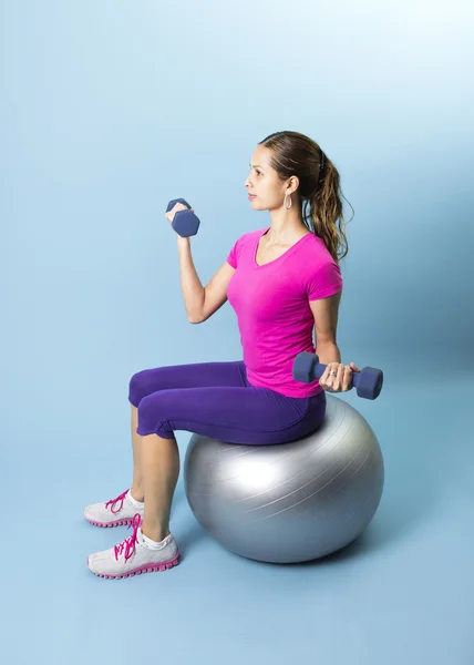 Fitness-Frau stemmt Gewichte auf Medizinball — Stockfoto