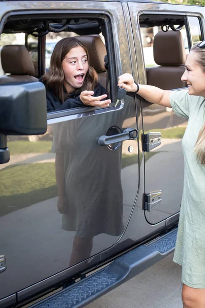 十几岁的女孩从她母亲那里得到汽车钥匙 获得驾驶执照和新车后 这个少女非常兴奋能开车 — 图库照片