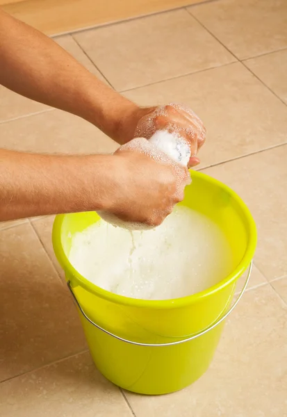 Händer vrider vatten ur en mopp trasa — Stockfoto