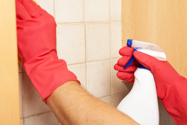 Hendene i gummihansker skrubber flisene på badet med en svamp – stockfoto