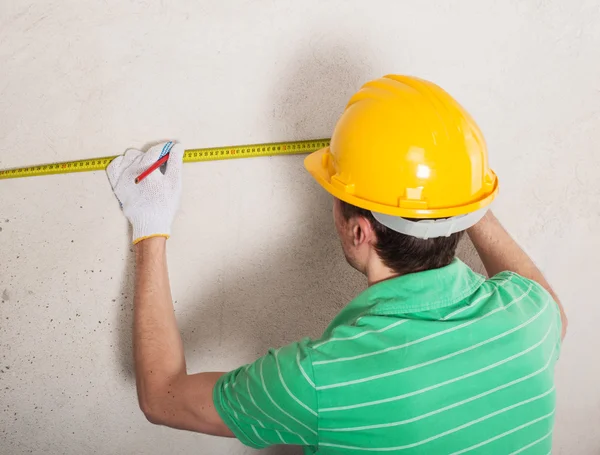 Worker measuring plaster wall — Stock Photo, Image