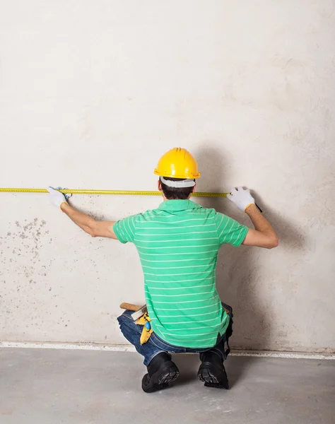 Worker measuring plaster wall — Stock Photo, Image