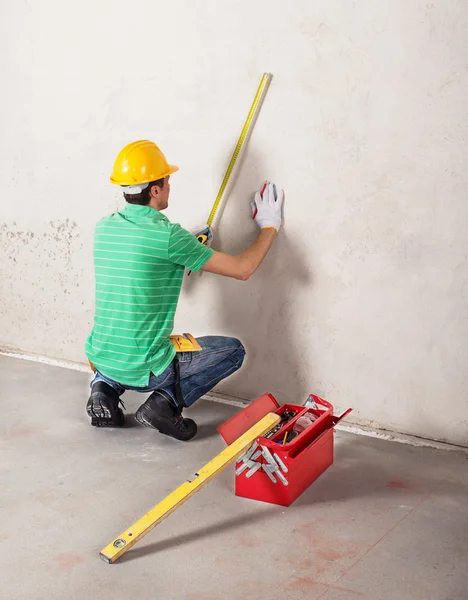 Worker measuring plaster wall — Stock Photo, Image