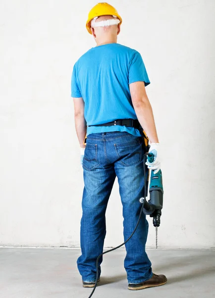 Arbeiter halten Bohrmaschine und stehen in der Nähe der Wand — Stockfoto