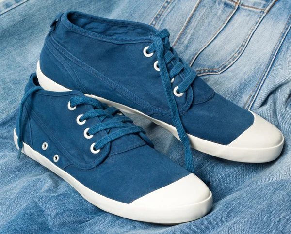 Een paar nieuwe blauwe schoenen op een jeans — Stockfoto
