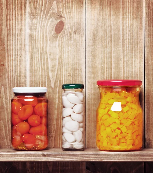 Preserved autumn vegetables on shelf near a brown wooden wall — Stock Photo, Image