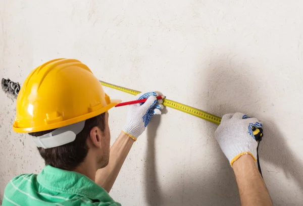 Worker measuring plaster wall — Stock Photo, Image